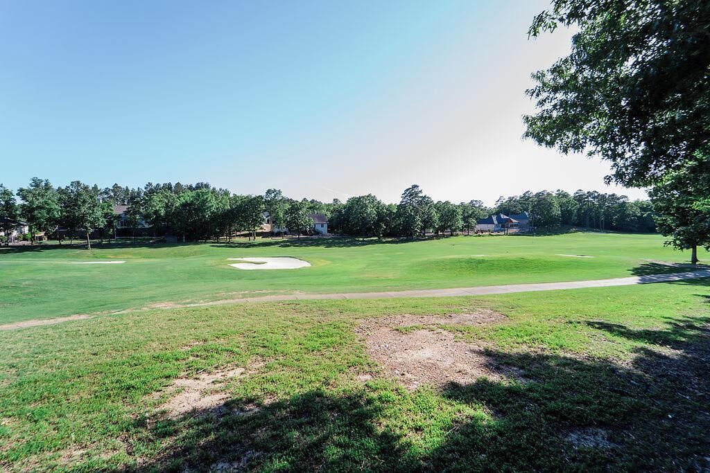 Un campo de golf con cielo despejado, un búnker de arena y un sendero que lleva al tee.