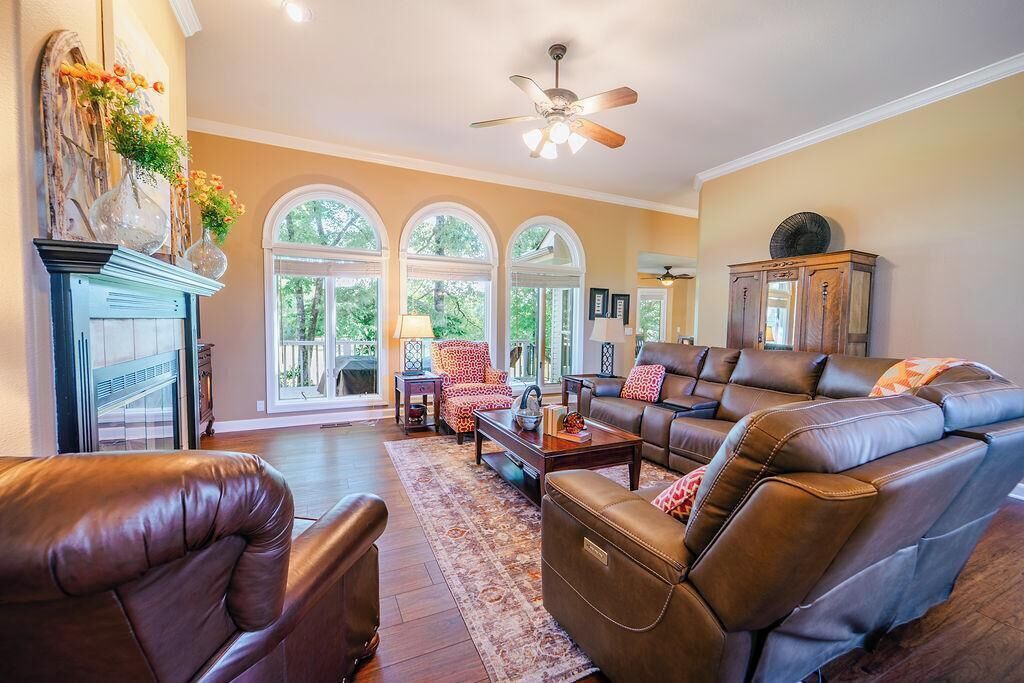 A spacious living room with leather sofas, a fireplace, and large windows.