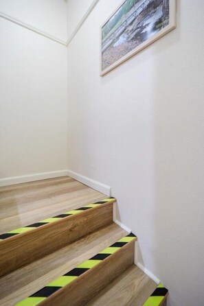 A staircase with wooden steps and a yellow and black striped riser. - Goldies Birdie Roost (Hot Springs Village)