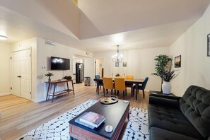 Un salon moderne comprenant un canapé, une table basse et un coin repas avec des chaises et une table.