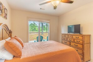 A bedroom with a bed, dresser, television, and a view of the outdoors. - Pepper's Pines and Putts, on Isabella golf course (Hot Springs Village)