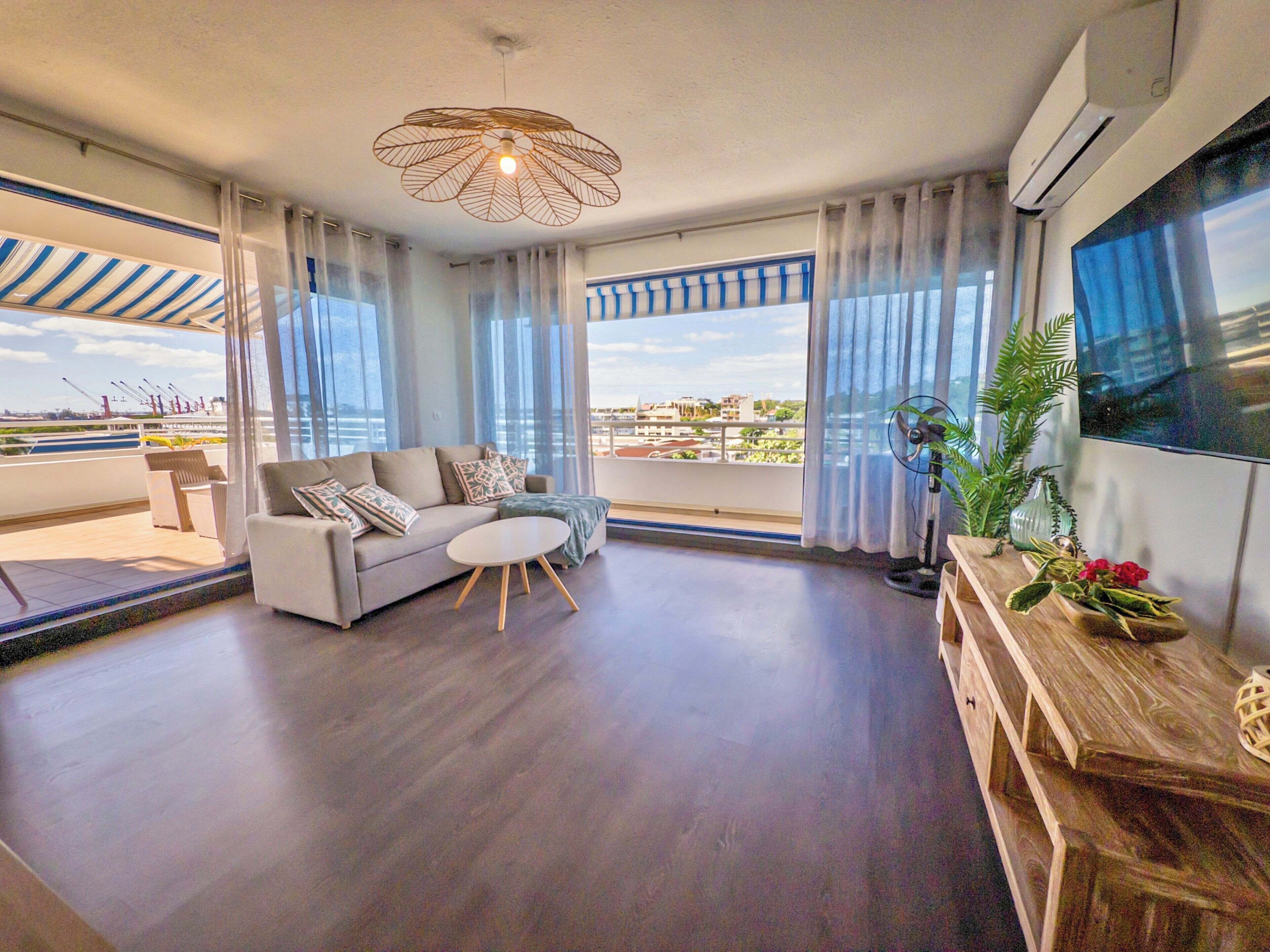 A modern living room with a sofa, a round coffee table, and a large window offering a view of the city.