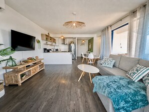 A modern living room with a grey sofa, a coffee table, and a TV mounted on the wall. - Teani Skyline | Downtown Papeete • Terrace • Moorea View • A/C • Parking (Papeete)