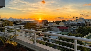 Vista do pôr do sol sobre um bairro residencial com edifícios e céu claro.