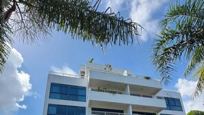Um edifício de vários andares com fachada plana, várias janelas e um estacionamento em frente.