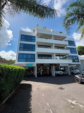 A multi-story building with a flat facade, multiple windows, and a parking area in front. - Teani Skyline | Downtown Papeete • Terrace • Moorea View • A/C • Parking (Papeete)
