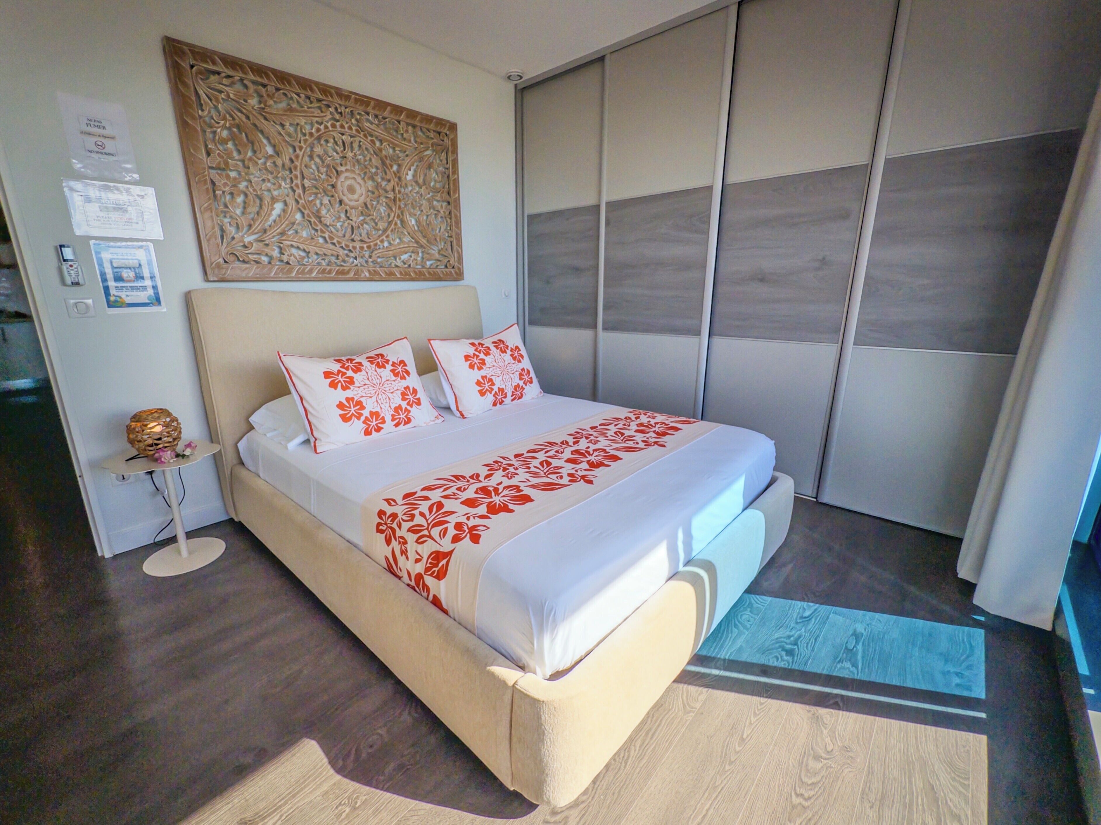 A modern bedroom with a large bed, a decorative wall panel, and a sliding door closet.