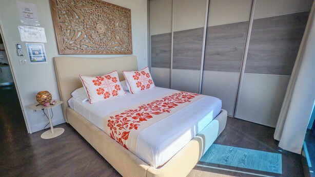Um quarto moderno com uma cama grande, um painel decorativo na parede e um armário com portas deslizantes.