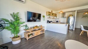Uma cozinha moderna com ilha central, eletrodomésticos embutidos e uma área de jantar com mesa e cadeiras brancas.