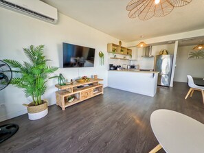 A modern kitchen with a central island, built-in appliances, and a dining area with a white table and chairs. - Teani Skyline | Downtown Papeete • Terrace • Moorea View • A/C • Parking (Papeete)
