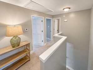 A hallway with a lamp, a console table, and a white railing.