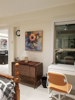 A room with a bed, a desk, a chair, a lamp, a clock, and a painting. - North Van Escape: Private 2BR Basement Near Grouse & Capilano Bridge (North Vancouver)