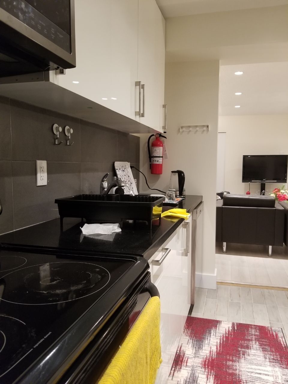 A modern kitchen with a black stove, white cabinets, and a yellow towel on the counter.