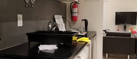 Una cucina moderna con piano cottura nero, mobili bianchi e un asciugamano giallo sul bancone.