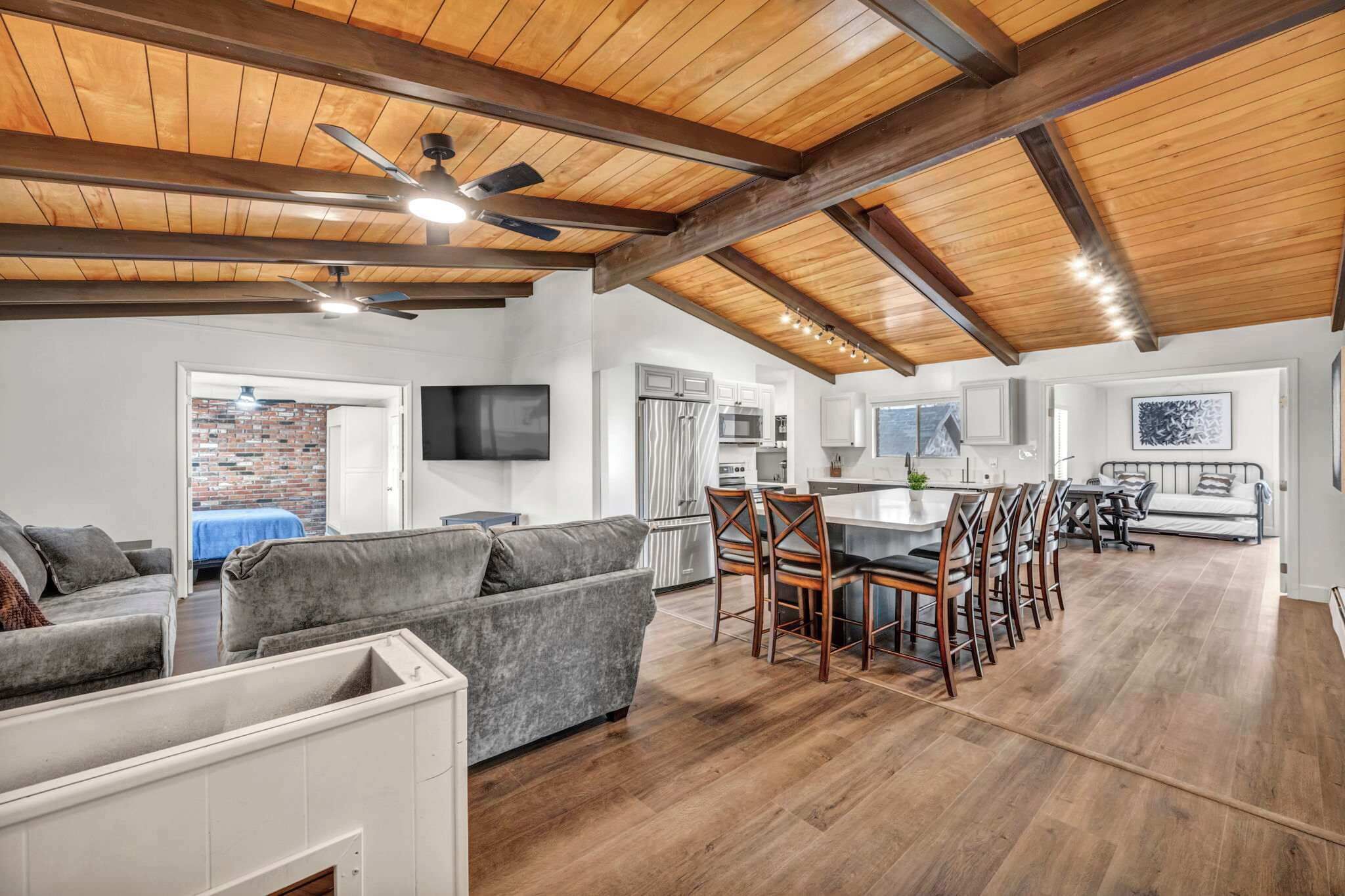 A spacious living area with a dining table and chairs, a kitchen with modern appliances, and a ceiling with exposed beams.