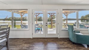 A room with a wooden floor, a teal chair, and a view of a dock and water. - All about that Bass lake house on beautiful lay lake (Shelby)