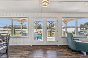 A room with a wooden floor, a teal chair, and a view of a dock and water. - All about that Bass lake house on beautiful lay lake (Shelby)