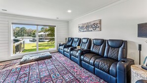 A room with a large window, a blue leather sofa, a patterned rug, and a sign on the wall. - All about that Bass lake house on beautiful lay lake (Shelby)