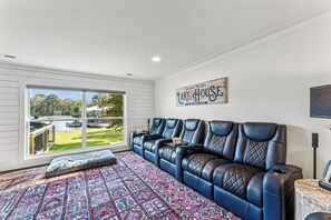 A room with a large window, a blue leather sofa, a patterned rug, and a sign on the wall. - All about that Bass lake house on beautiful lay lake (Shelby)