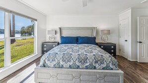 A bedroom with a large bed, two bedside tables, a ceiling fan, and a view of a lake. - All about that Bass lake house on beautiful lay lake (Shelby)