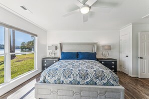 A bedroom with a large bed, two bedside tables, a ceiling fan, and a view of a lake. - All about that Bass lake house on beautiful lay lake (Shelby)