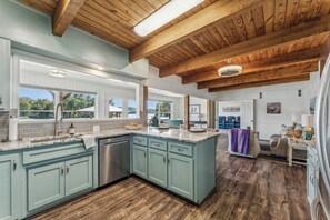 A spacious kitchen with light blue cabinets, a large island, and wooden beams on the ceiling.
