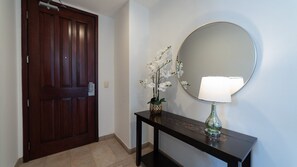 Eine Holztür, ein Konsolentisch mit Spiegel und Lampe, sowie eine Orchidee im Topf.