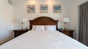 Una habitació d'hotel amb un llit gran, dues taules de nit amb làmpades i tres quadres a la paret.