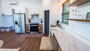 A modern kitchen with white cabinetry, stainless steel appliances, and a marble countertop. - Wild Finch Stay - Sauna • Cold Plunge • Hot Tub (Colorado Springs)