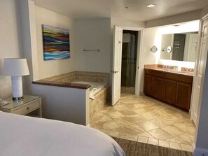 A hotel room with a bed, a bathroom with a bathtub, a sink, and a mirror.