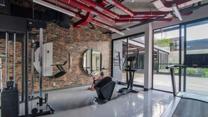 A gym with exercise equipment, a brick wall, and large windows. - Liva Escalante Sky Retreat | Panoramic City Views & Walking Distance to Restaurants (San José)