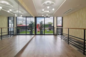 Ein geräumiges Zimmer mit modernem Design, ausgestattet mit einem großen Glastür, der zu einem Außenbereich mit Grünflächen und einer roten Struktur führt.