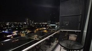 A balcony with a glass railing, two wicker chairs, and a small table. - Liva Escalante Sky Retreat | Panoramic City Views & Walking Distance to Restaurants (San José)