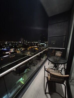 Ein Balkon mit Glastrennwand, zwei Korbstühle und ein kleiner Tisch.