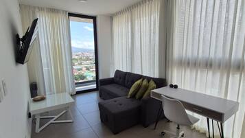Una sala de estar moderna con sofá, reposapiés y un escritorio con una silla.