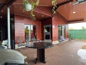 An outdoor patio with a round table and chairs, surrounded by wooden walls and large windows. - 4-bedroom house with AC in La Fortuna (La Fortuna)
