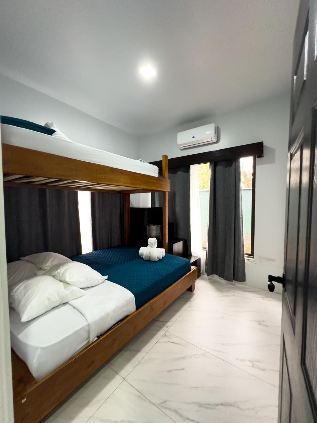 Un letto a castello con un materasso blu, cuscini bianchi e un asciugamano bianco sulla cuccetta inferiore.