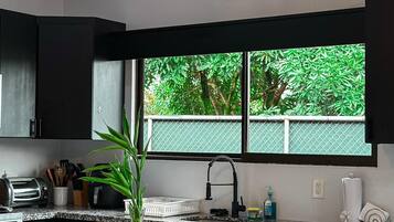 Una cucina moderna con un piano di lavoro in granito, uno schienale bianco e nero, un forno integrato e una finestra con vista sul verde.