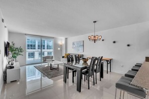 A modern living room with a glass dining table, black chairs, and a chandelier. - The Club Brickell | 39th Floor Bay View (Miami)