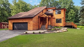 A log cabin with a garage, a front porch, and a staircase leading to a deck. - Winter Court by Avantstay Game Room Private Basketball Court Fire Pit Near Skiing & Raceway (Pocono Summit)