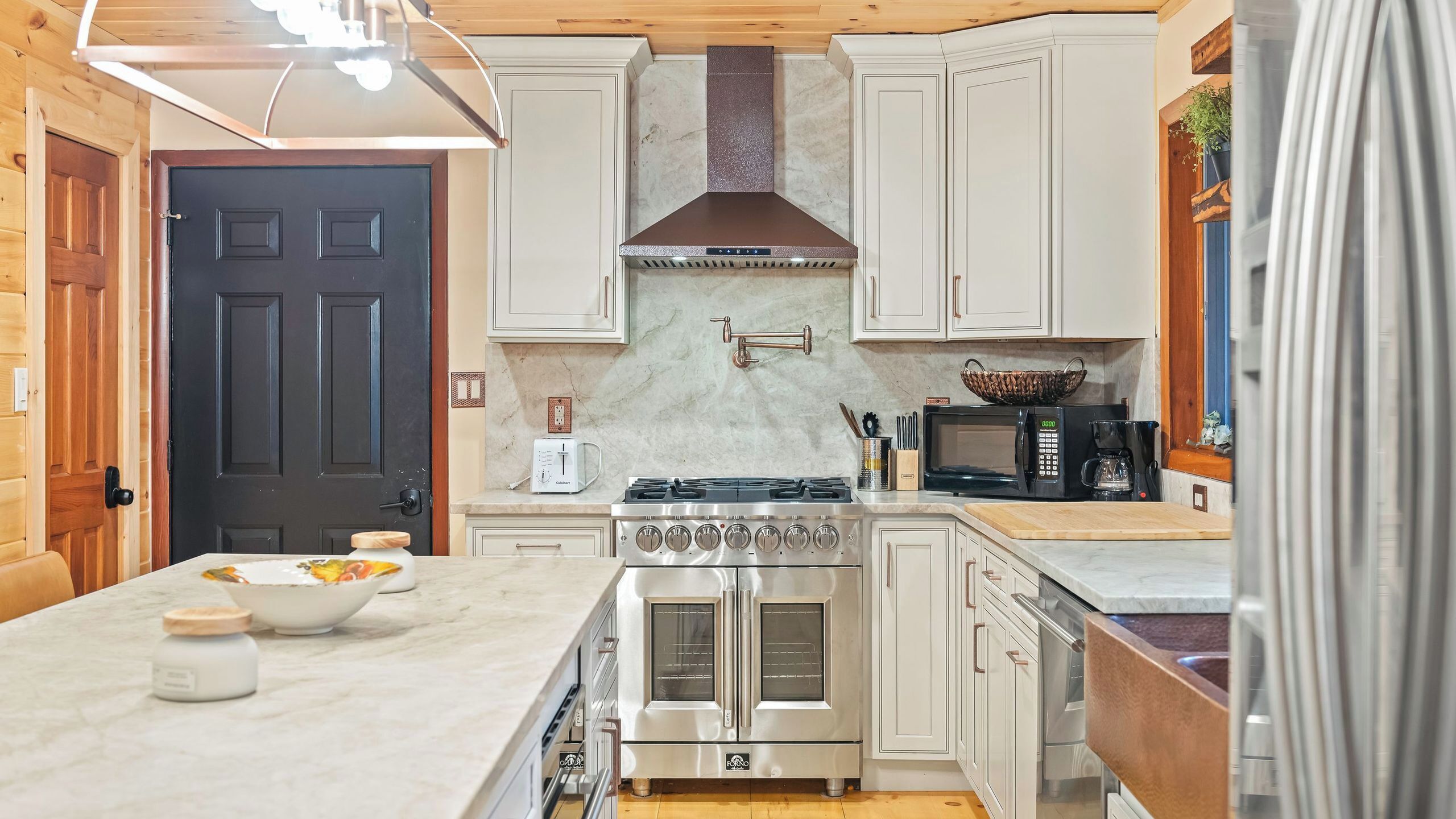 A compact kitchen with a stove, microwave, and a small sink.