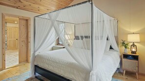 A four-poster canopy bed with white bedding, a bedside table with a lamp, and a wooden floor. - Winter Court by Avantstay Game Room Private Basketball Court Fire Pit Near Skiing & Raceway (Pocono Summit)