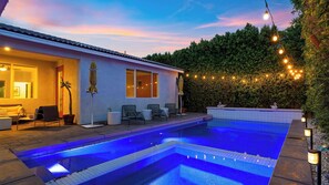 A swimming pool with a tiled deck, a patio with chairs and a table, and string lights. - The Encore by Avantstay Pool + Hot Tub + Outdoor Pool Table + Fire Pit Mins to the Polo Fields (Indio)