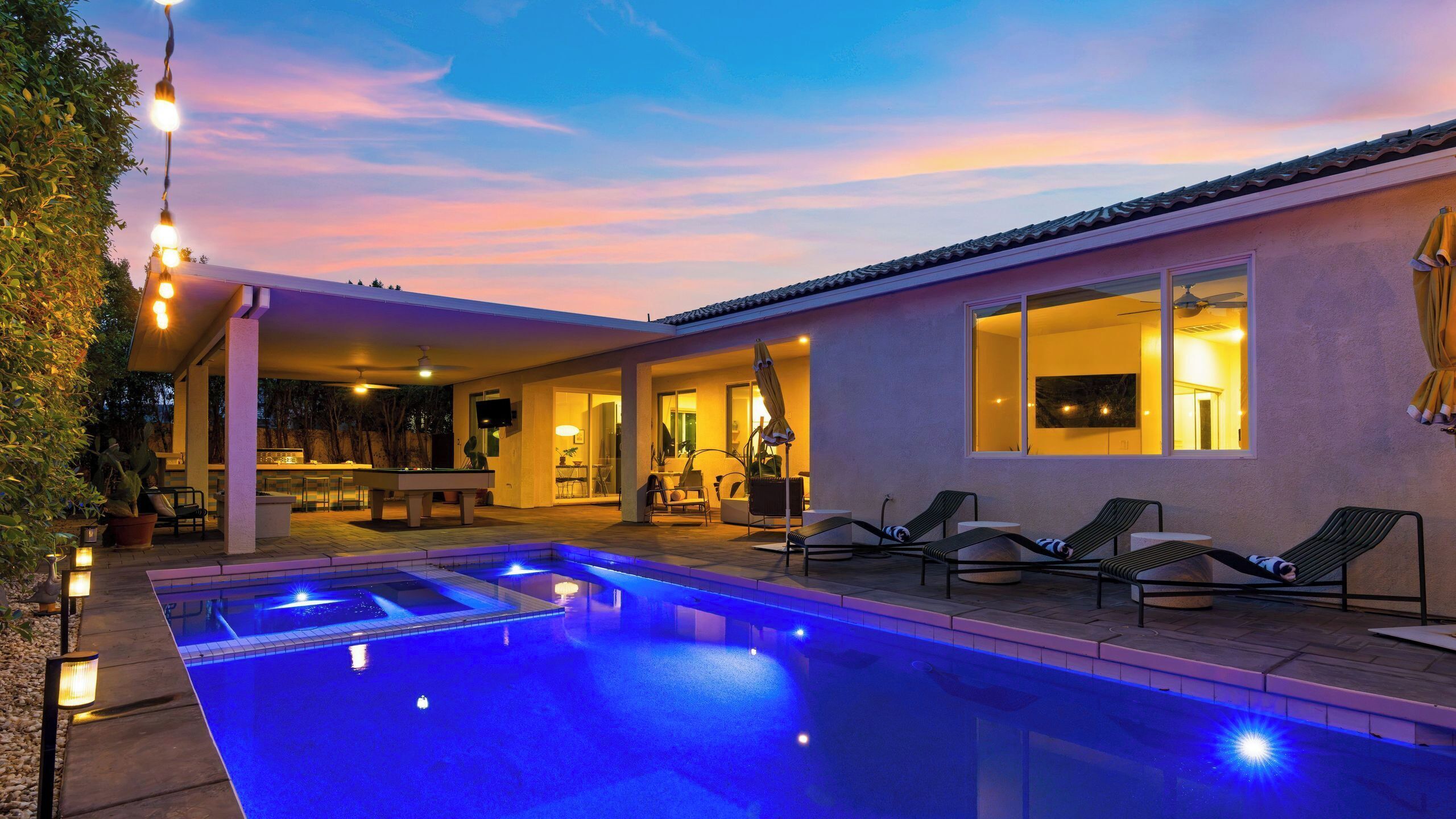 A swimming pool with lounge chairs and a covered patio area.