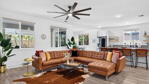Un salon moderne avec un canapé d’angle, une table basse et un ventilateur de plafond.
