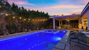 Une piscine avec un espace patio, des guirlandes lumineuses et un coin salon abrité.