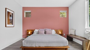 Ein Schlafzimmer mit Bett, Nachttischen, einer Bank und einem Fenster.