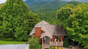 Eine Hütte mit Veranda, umgeben von dichtem Wald und Bergen.