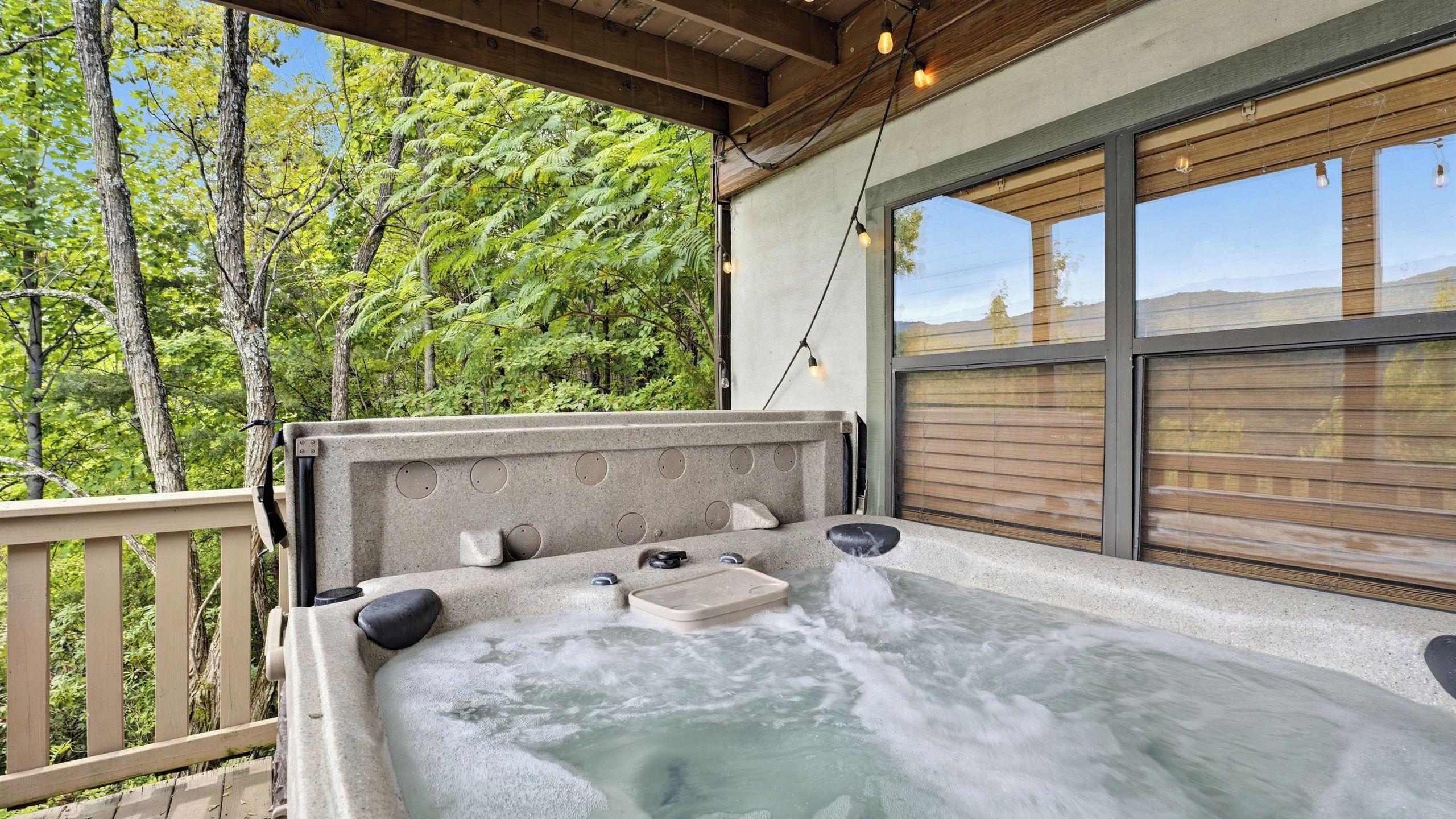 A hot tub with a wooden deck and a view of trees.