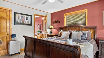 A bedroom with a wooden bed, a nightstand, a lamp, and a window with blinds.